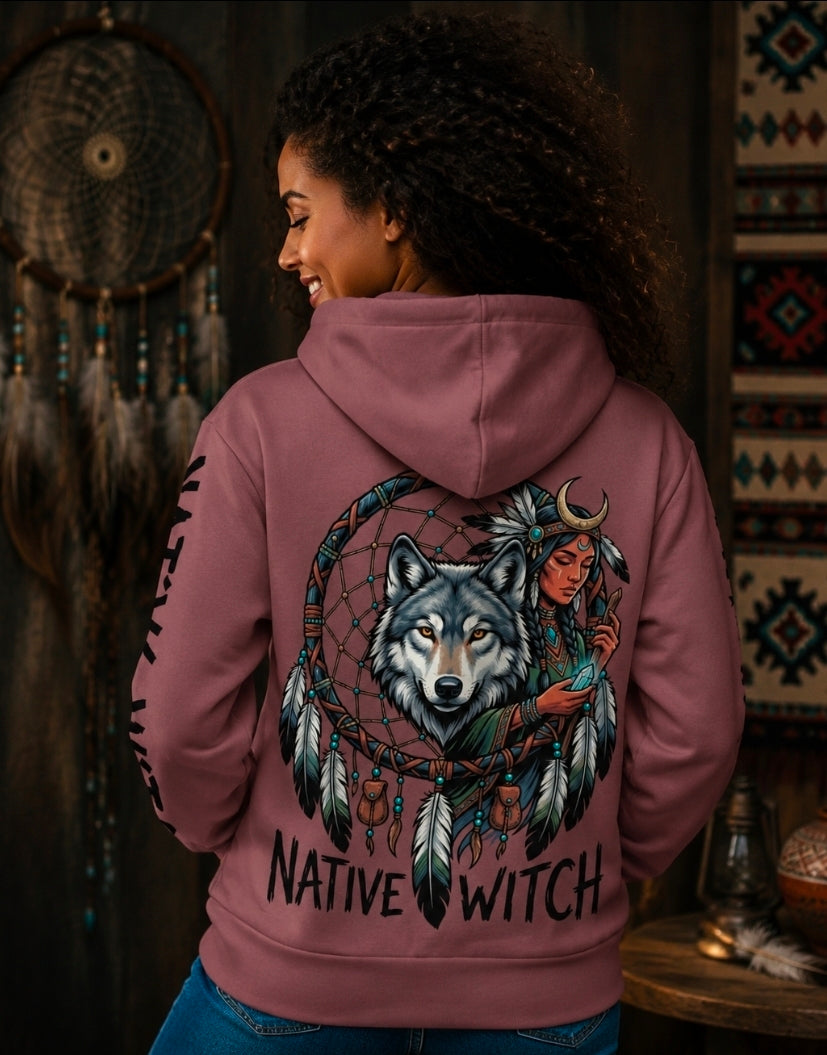 A woman shown from the back wearing a dusty rose hoodie with a large graphic print of a wolf, dreamcatcher, and a Native American woman, with the text 'NATIVE WITCH' printed below.