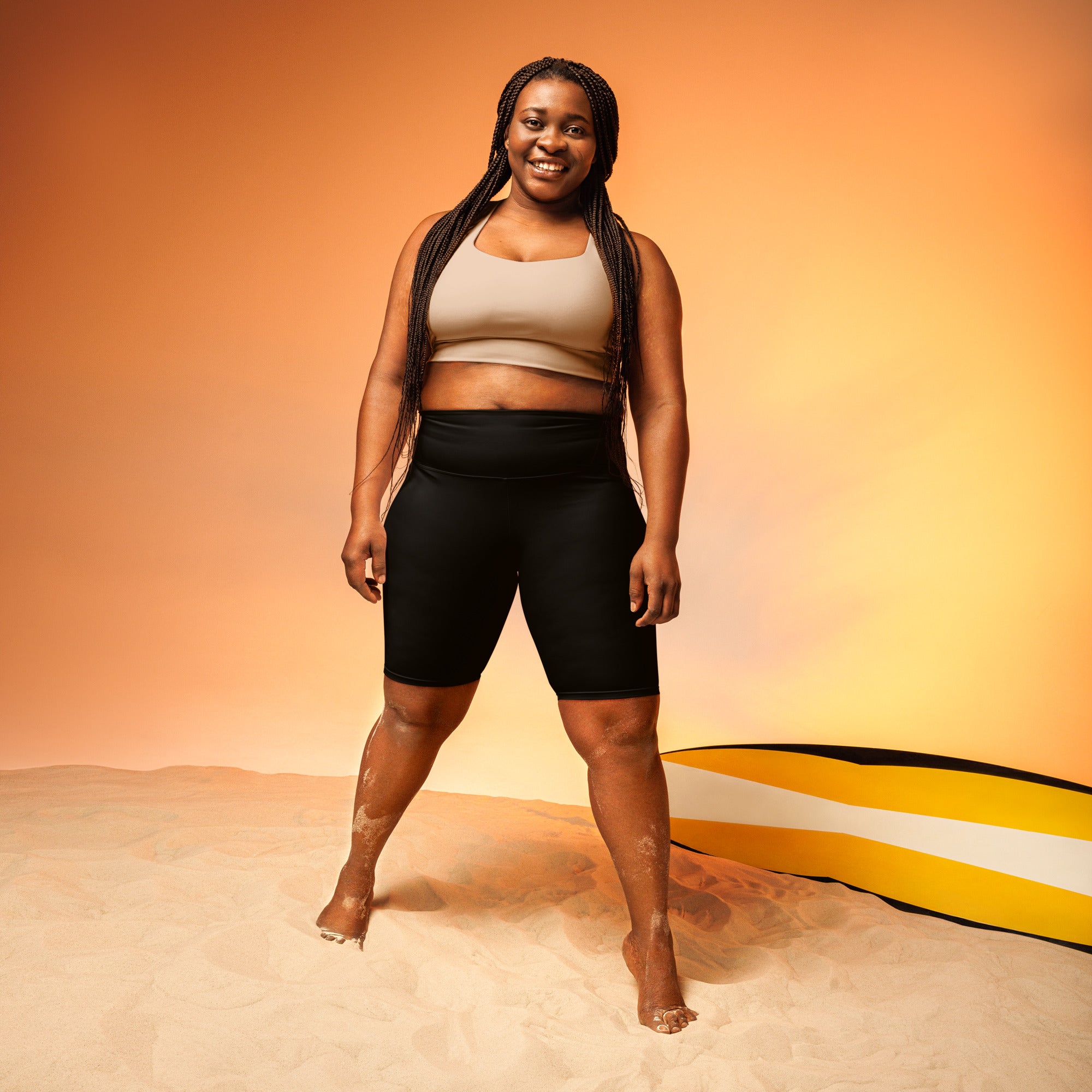 Woman in athletic wear biker shorts standing on sand with a colorful background